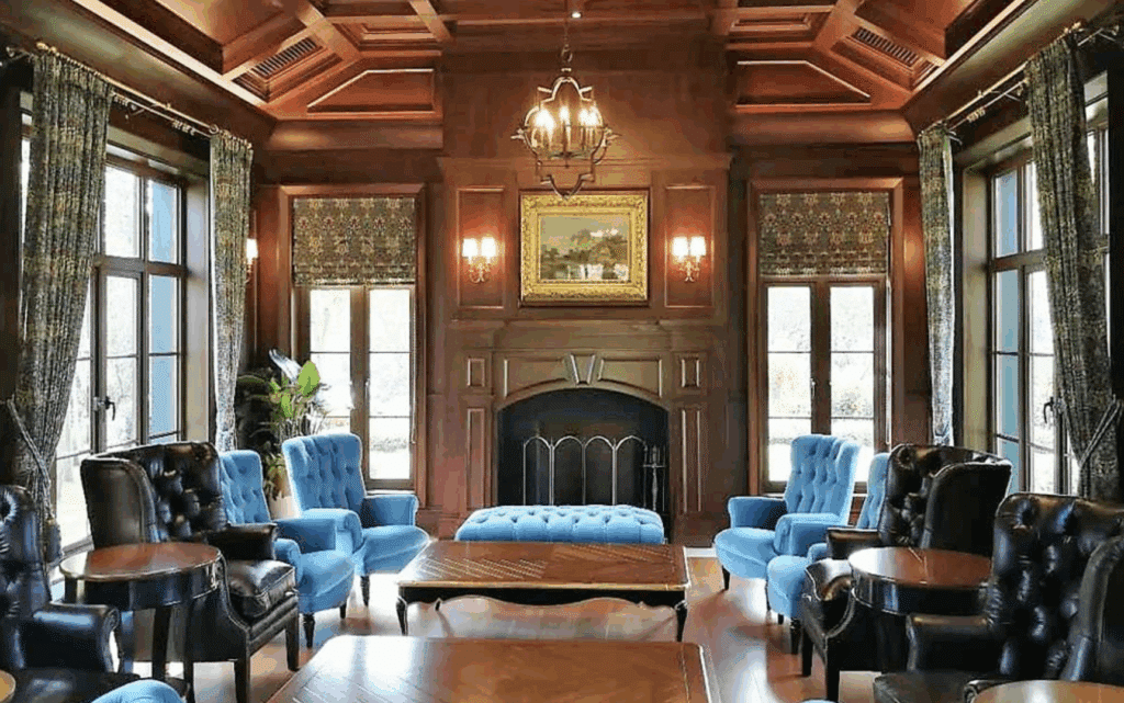 Formal library room with fireplace, blue chairs, and classic architectural details.